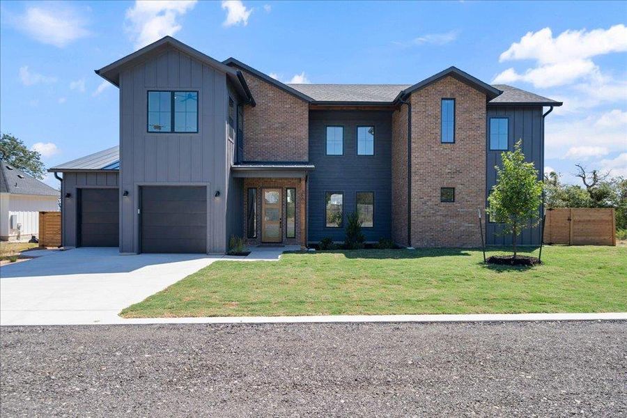 Modern farmhouse with board and batten siding, concrete driveway, and brick siding