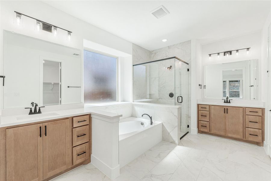 Master bathroom with dual wood vanities, soaking tub, glass shower, and marble tile floors Master bathroom with dual wood vanities, soaking tub, glass shower, and marble tile floors