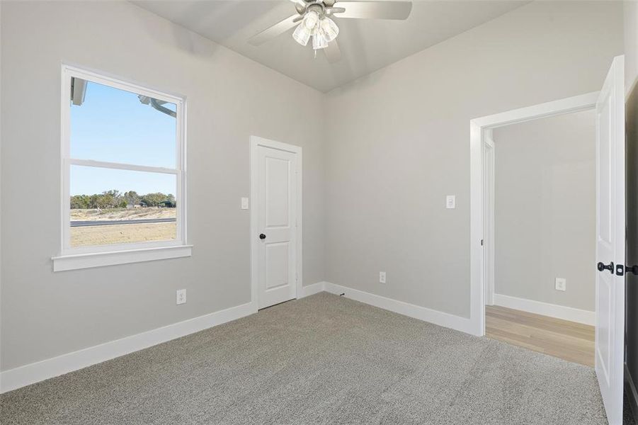 Unfurnished room with light colored carpet and ceiling fan Unfurnished room with light colored carpet and ceiling fan
