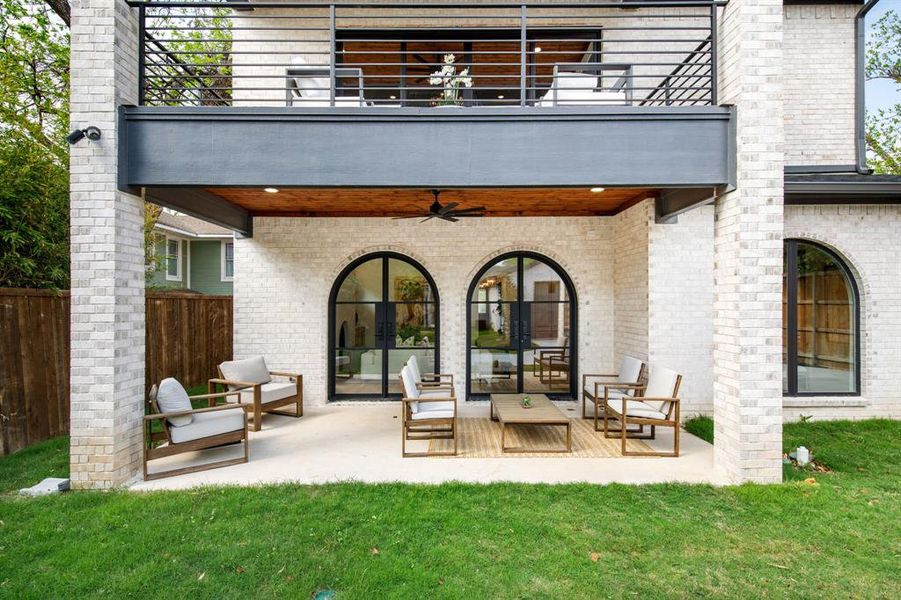 Covered outdoor patio featuring arched black-frame doors, a wood-finish ceiling with recessed lighting, and a ceiling fan Covered outdoor patio featuring arched black-frame doors, a wood-finish ceiling with recessed lighting, and a ceiling fan
