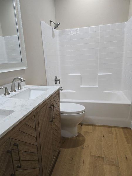 Full bathroom with  shower combination, vanity, hardwood / wood-style floors, and toilet