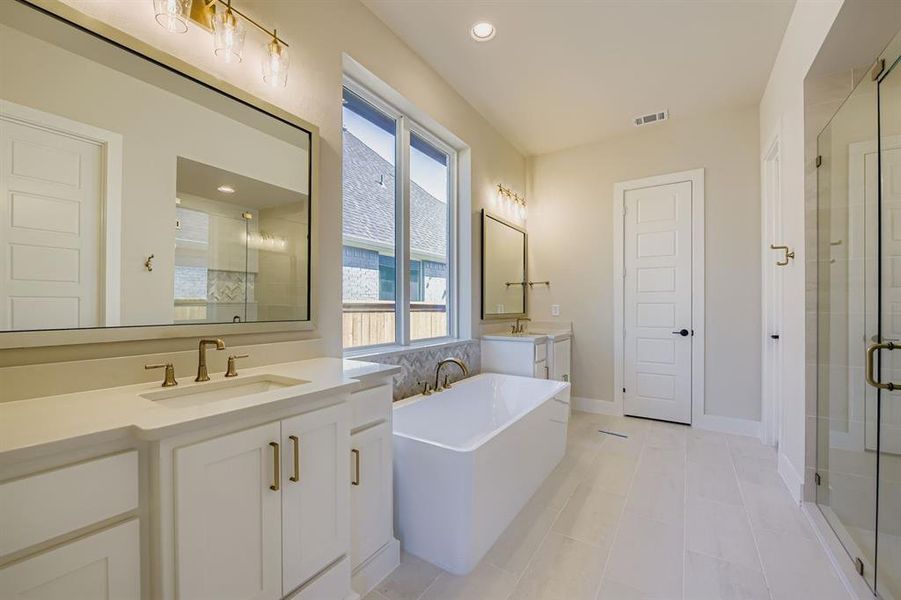Full bath featuring a shower stall, two vanities, a freestanding tub, recessed lighting, and light tile patterned flooring