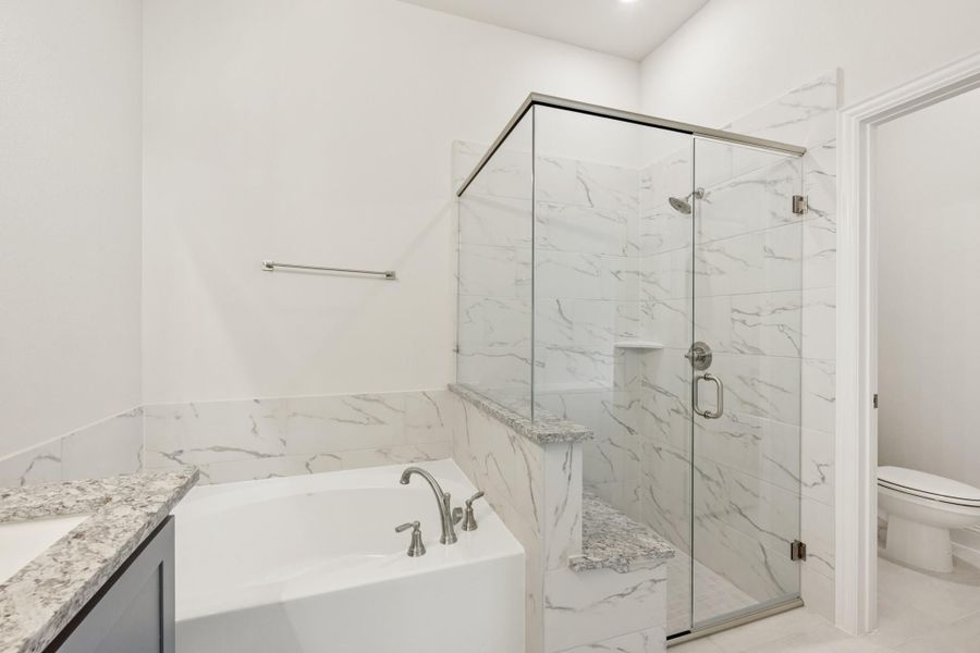 Master bathroom with soaking tub, glass walk-in shower, and marble tile walls