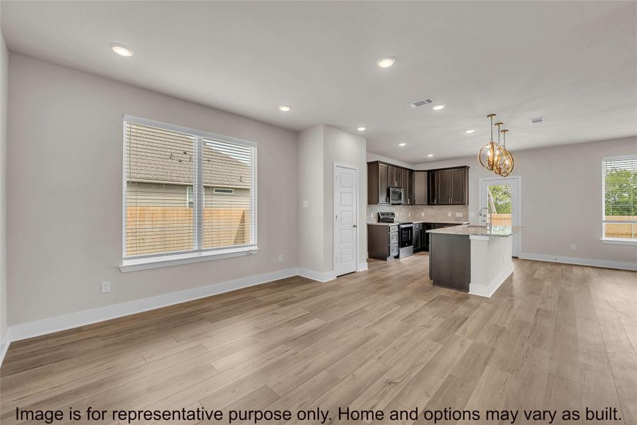 Kitchen featuring dark wood finish cabinets, a center island with sink, open floor plan, a chandelier, and stainless steel appliances