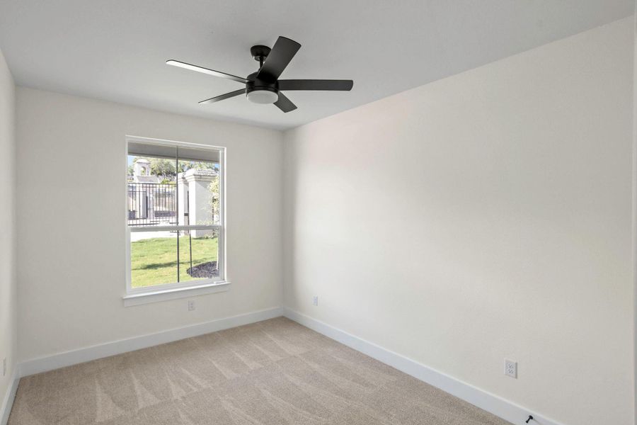 Neutral-toned room featuring a single window, a ceiling fan with integrated lighting, and light-colored carpet flooring Neutral-toned room featuring a single window, a ceiling fan with integrated lighting, and light-colored carpet flooring