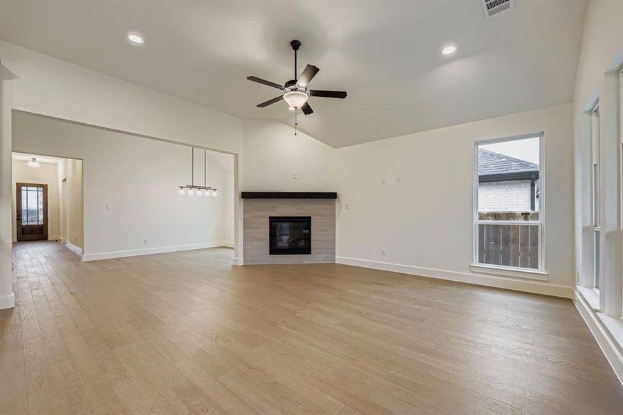 Unfurnished living room featuring lofted ceiling, light wood-type flooring, ceiling fan, recessed lighting, and a fireplace