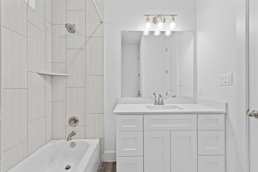 Bathroom with tiled shower / bath combo and vanity