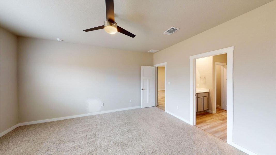 Unfurnished bedroom featuring light carpet, a ceiling fan, and ensuite bath