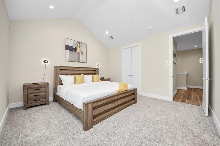 The primary suite feels noticeably open thanks to its vaulted ceiling, multiple windows, and direct connection to the private bath.