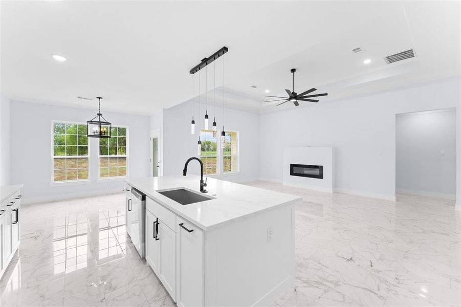 Kitchen with a kitchen island with sink, sink, ceiling fan, stainless steel dishwasher, and white cabinets