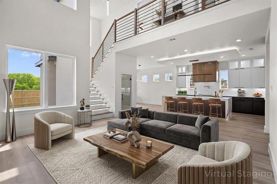 Spacious living area with high ceilings, large windows, and light wood flooring Spacious living area with high ceilings, large windows, and light wood flooring