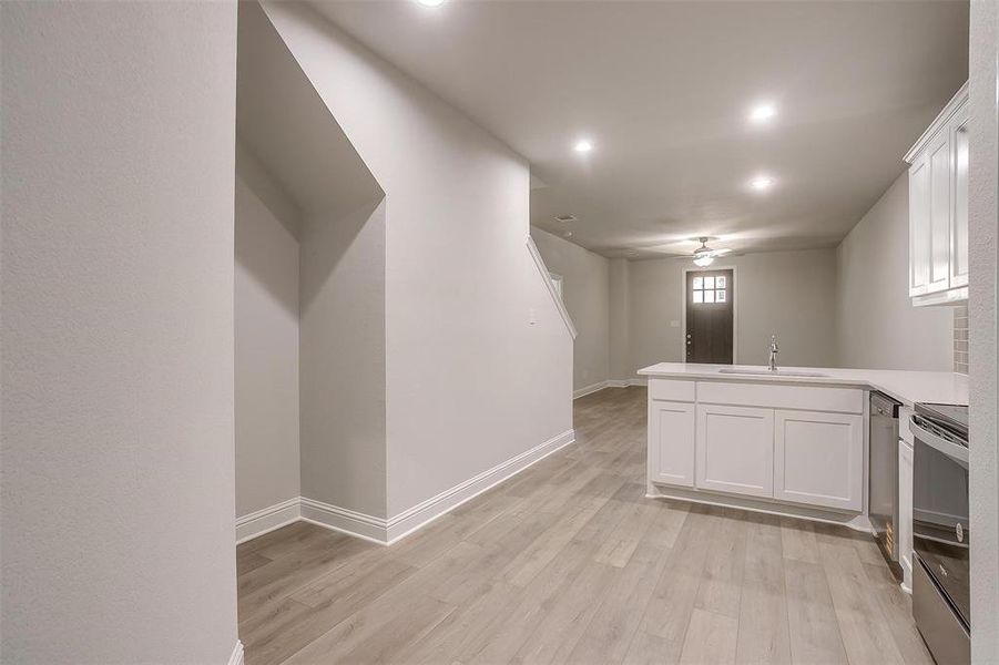 Kitchen with a ceiling fan, a peninsula, range with electric stovetop, white cabinetry, and light wood-type flooring Kitchen with a ceiling fan, a peninsula, range with electric stovetop, white cabinetry, and light wood-type flooring