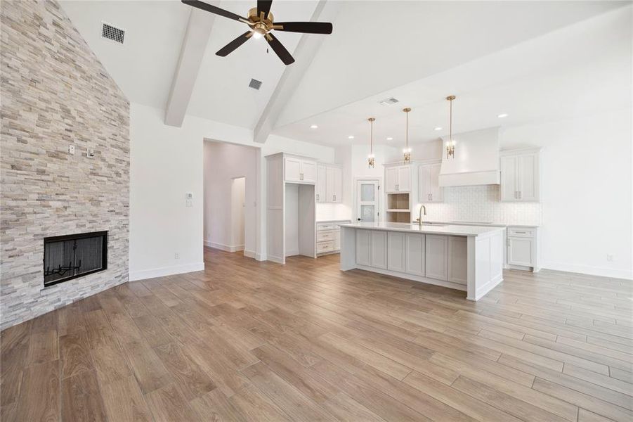 Kitchen with decorative backsplash, sink, pendant lighting, a center island with sink, and white cabinets