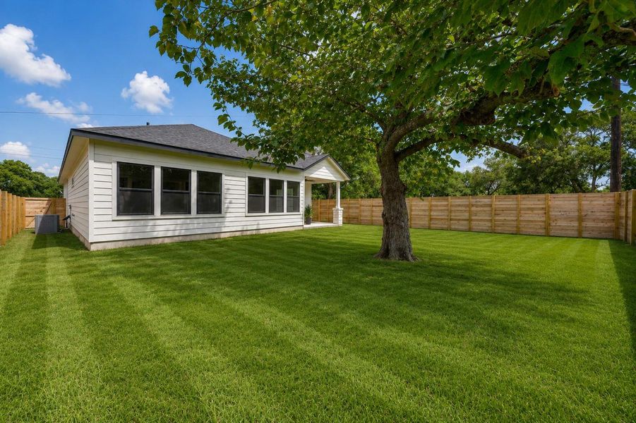 A broad, verdant lawn encircles this crisp white home, fully enclosed by a new wooden privacy fence. A broad, verdant lawn encircles this crisp white home, fully enclosed by a new wooden privacy fence.