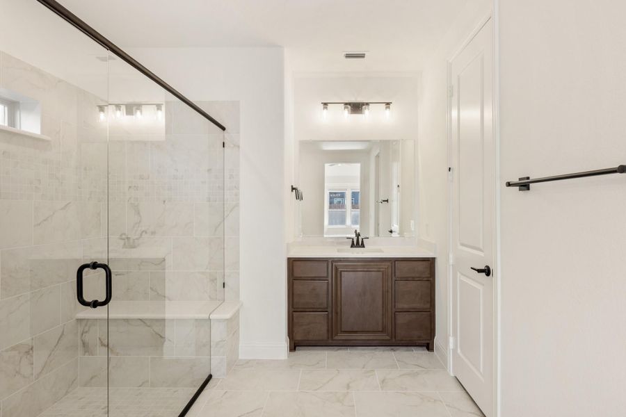 Bathroom with glass walk-in shower, marble tile, and dark wood vanity with white countertop
