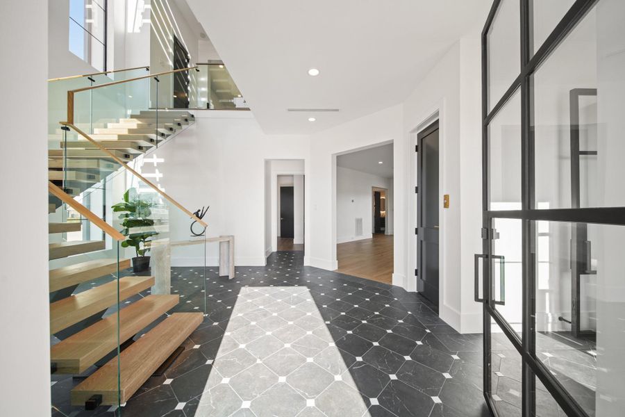 Upon entry to the foyer, you are greeted with beautiful art deco tile and modern floating stairs with glass panel railings.