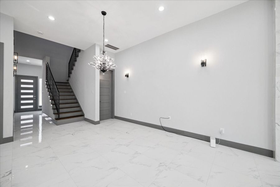 In the entry, bold lighting and sleek sconces create a welcoming atmosphere, complemented by an open design that leads naturally to the staircase and central living areas.