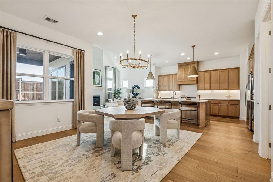 Dining area featuring a chandelier, light wood finished floors, and a large fireplace