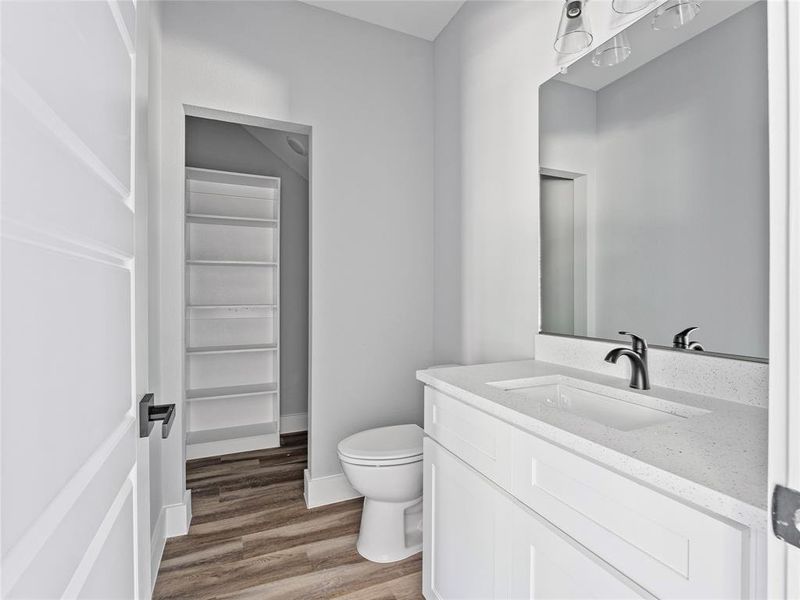 Bathroom featuring toilet, wood finished floors, vanity, and baseboards