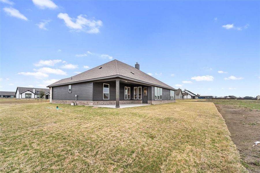 Back of property with a patio, a lawn, a shingled roof, and a chimney