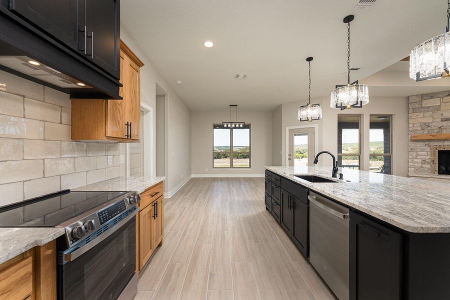 Kitchen featuring dark cabinets, stainless steel appliances, open floor plan, light stone counters, and recessed lighting Kitchen featuring dark cabinets, stainless steel appliances, open floor plan, light stone counters, and recessed lighting