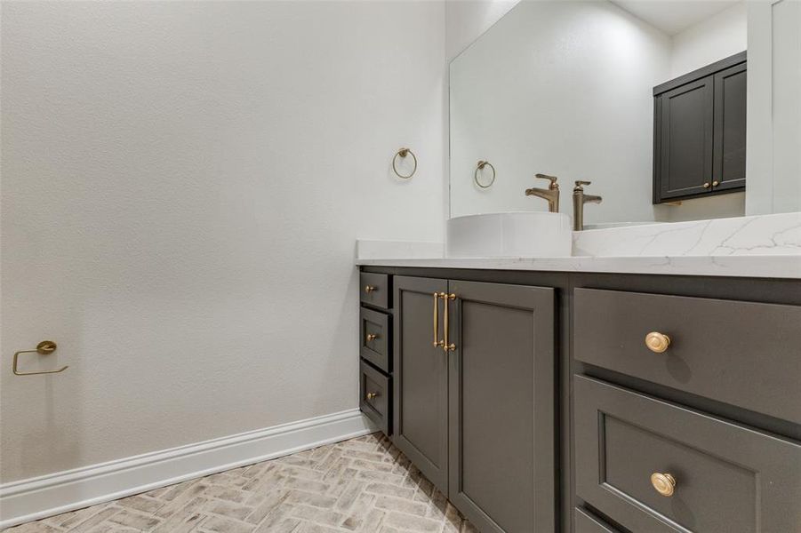 Bathroom featuring baseboards, brick patterned flooring, and vanity