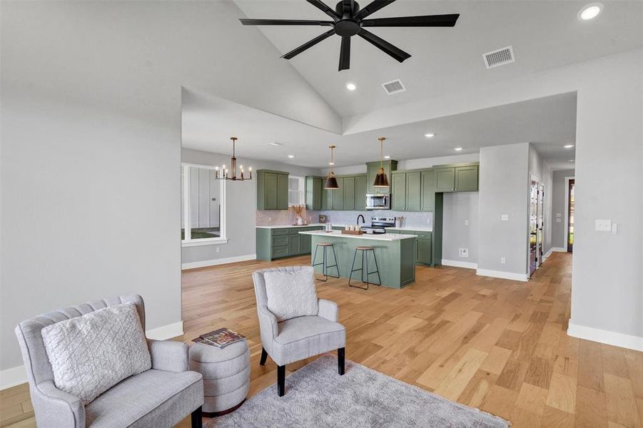 Living area with a chandelier, light wood-style floors, recessed lighting, a ceiling fan, and high vaulted ceiling Living area with a chandelier, light wood-style floors, recessed lighting, a ceiling fan, and high vaulted ceiling
