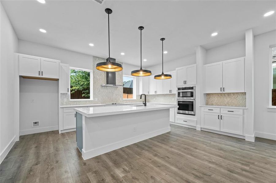 Kitchen featuring stainless steel double oven, light countertops, white cabinets, and recessed lighting Kitchen featuring stainless steel double oven, light countertops, white cabinets, and recessed lighting