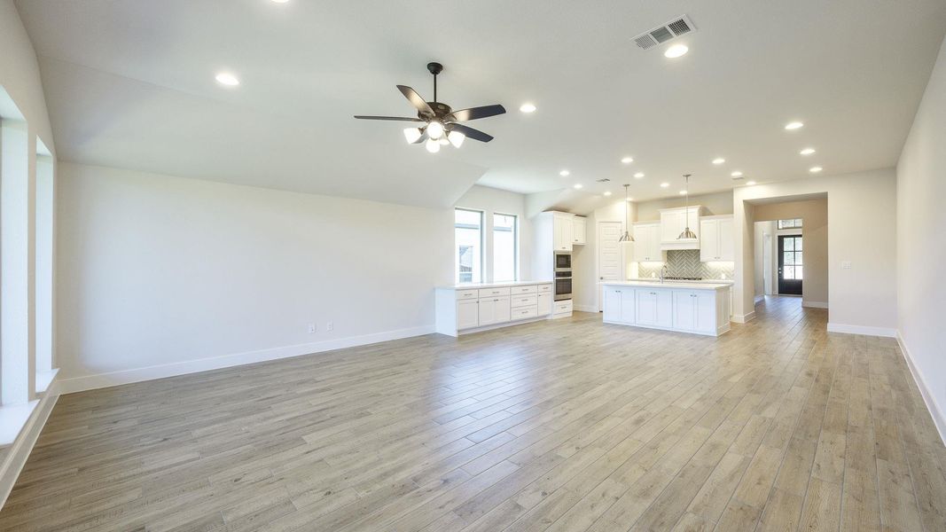Unfurnished living room featuring recessed lighting, light wood-type flooring, a ceiling fan, and vaulted ceiling Unfurnished living room featuring recessed lighting, light wood-type flooring, a ceiling fan, and vaulted ceiling