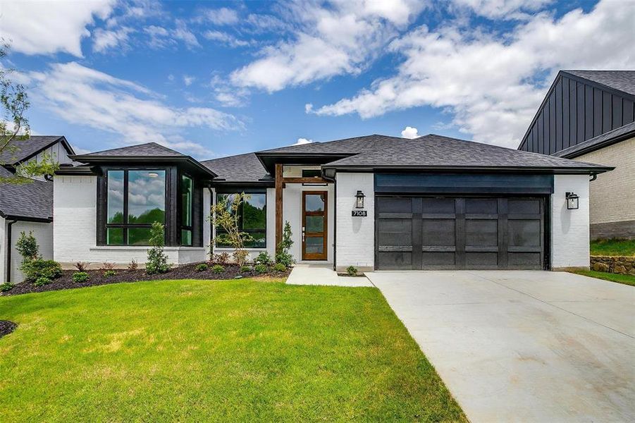 View of front of property featuring a front yard and a garage