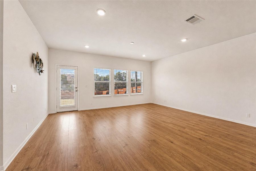 Living area showcasing recessed lighting, rich hardwood flooring and outdoor access.