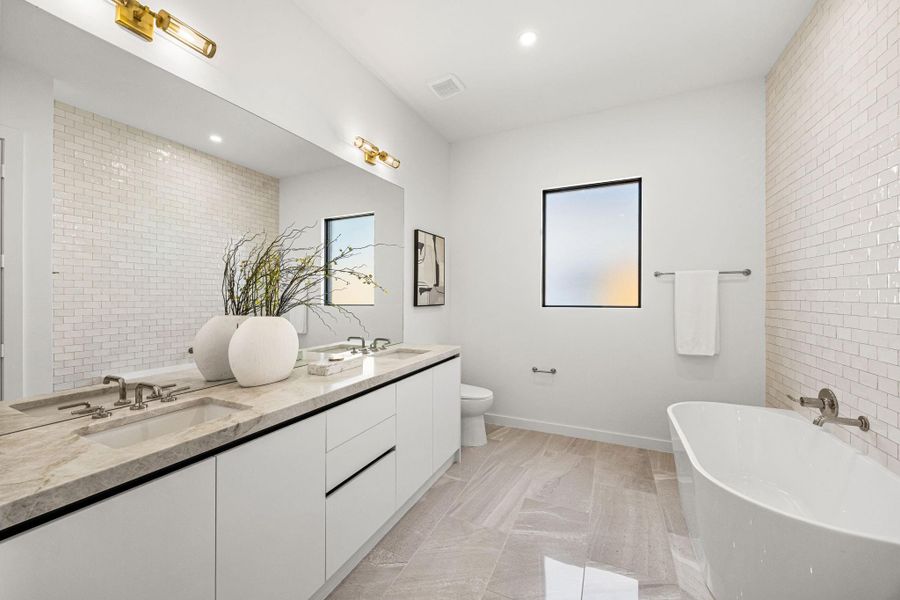 Secondary bath also offers a soak tub & walk-in shower w/ a vast wall of zellige tile & dual vanities.
