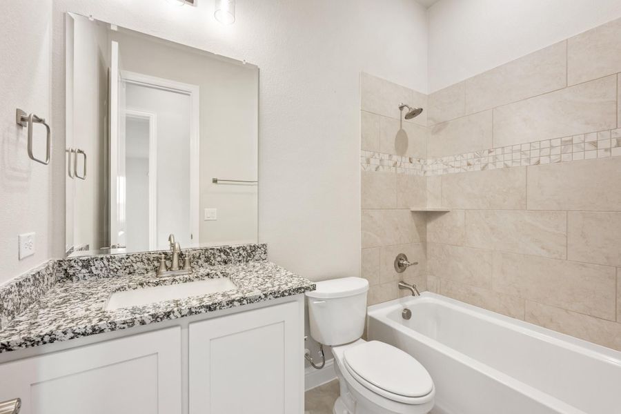 Bathroom with granite vanity, white cabinets, and tiled tub-shower combo with mosaic accent strip Bathroom with granite vanity, white cabinets, and tiled tub-shower combo with mosaic accent strip