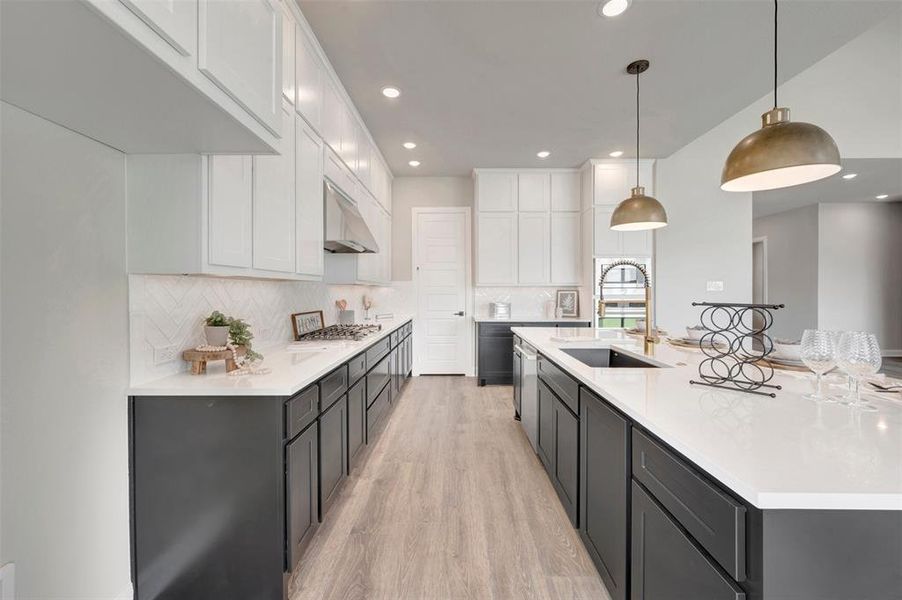 Modern kitchen featuring an expansive island with a built-in sink and two pendant lights