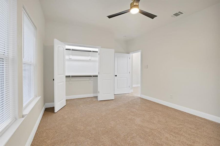 Unfurnished bedroom with ceiling fan, light colored carpet, and a closet