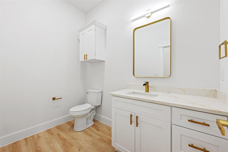 Bathroom featuring a vanity with a stone countertop, an undermount sink, and a gold-finish faucet