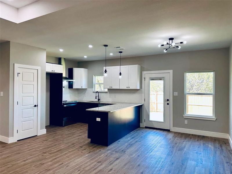 Kitchen with tons of natural light, dual colored cabinetry, lovely white backsplash, granite countertops.