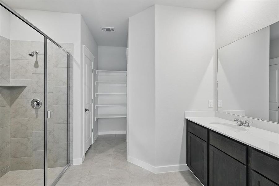 Bathroom featuring vanity, a shower stall, a walk in closet, and light tile patterned floors