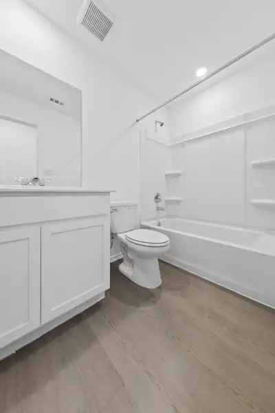 Bathroom featuring vanity, shower / bath combination, light wood-style floors, and recessed lighting