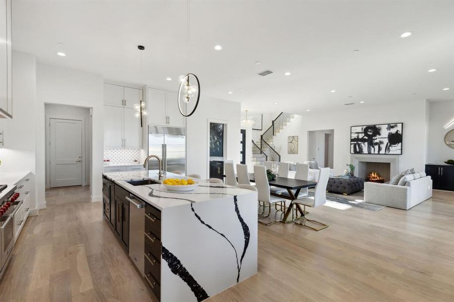 Kitchen featuring a center island with sink, white cabinets, built in fridge, and light wood-type flooring