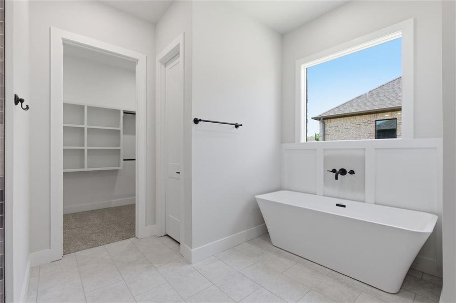 Freestanding soaking tub with wall-mounted matte black fixtures