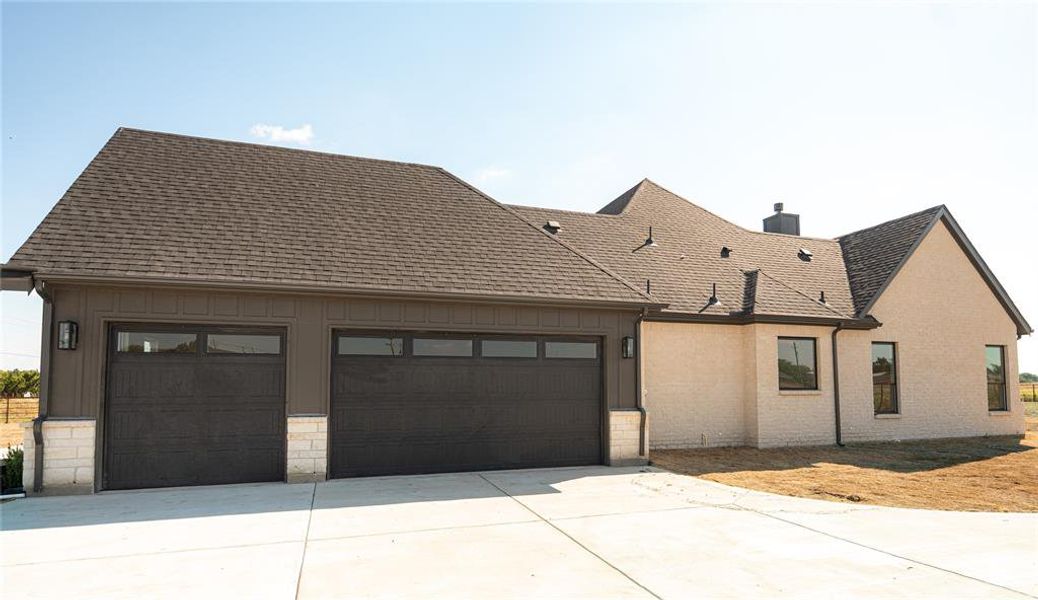 View of front of property with driveway, a garage, roof with shingles, and a chimney