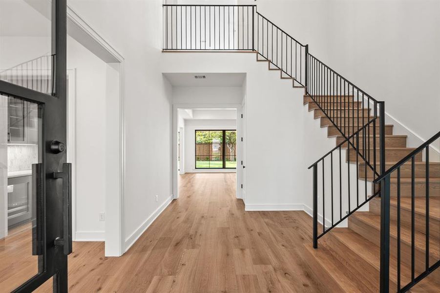 Foyer entrance featuring a high ceiling, light wood-style floors, and stairs Foyer entrance featuring a high ceiling, light wood-style floors, and stairs