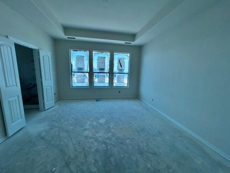Unfurnished bedroom featuring a tray ceiling and baseboards