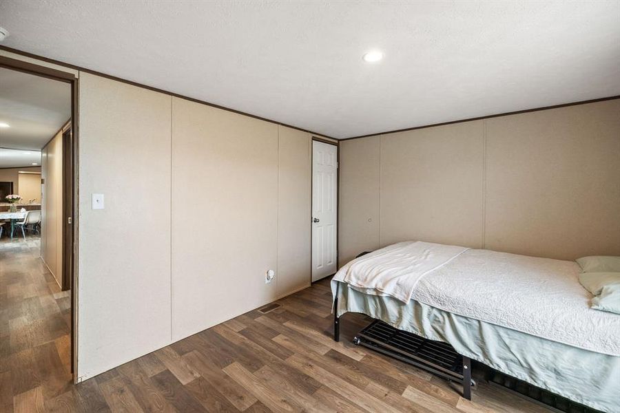 Room featuring wood-finish flooring, recessed ceiling lighting, and a white interior door Room featuring wood-finish flooring, recessed ceiling lighting, and a white interior door
