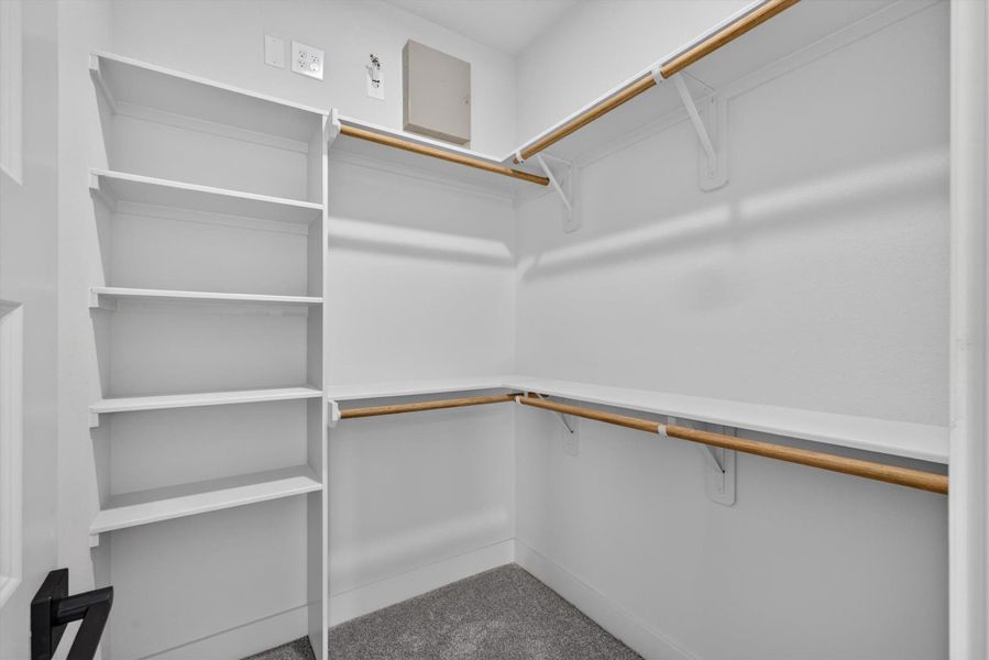 This photo shows a spacious walk-in closet with double hanging rods and built-in shelving, providing ample storage space. The neutral gray walls and white trim create a modern, clean look. This photo shows a spacious walk-in closet with double hanging rods and built-in shelving, providing ample storage space. The neutral gray walls and white trim create a modern, clean look.