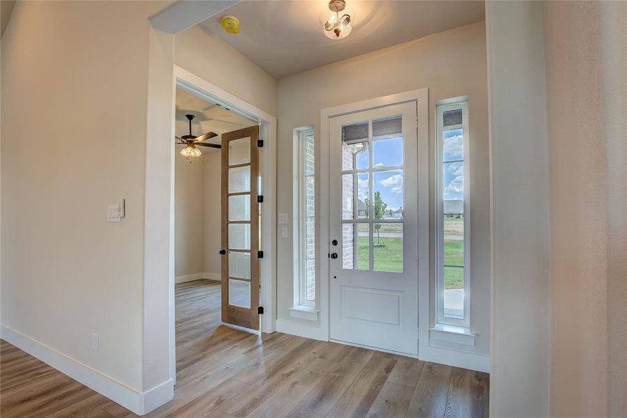 Foyer entrance with ceiling fan and light wood-type flooring