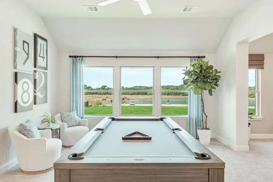 Game room with pool table, seating area, and large windows overlooking a pond and green lawn