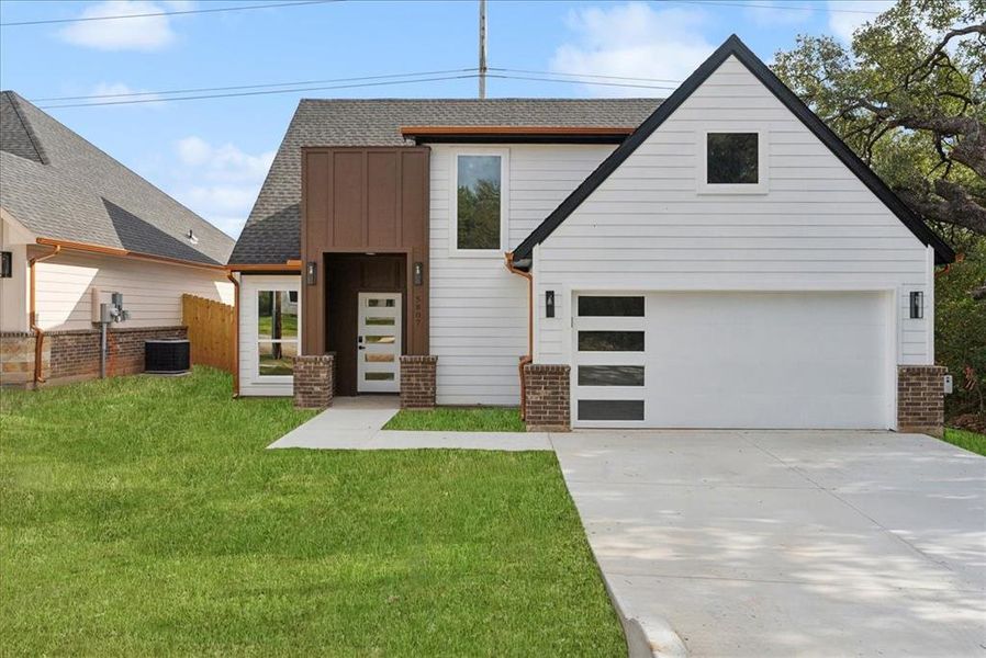 View of front of property featuring a front yard, central AC unit, and a garage