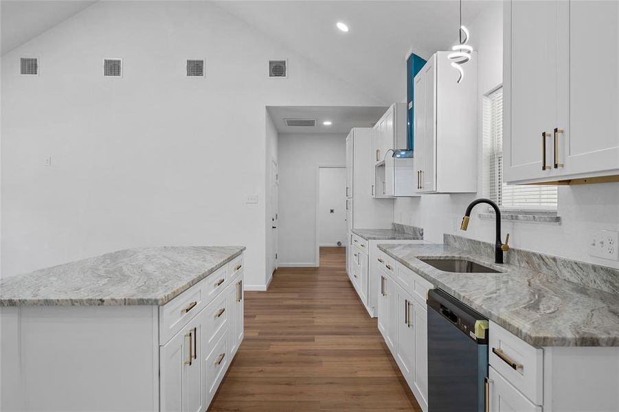 Kitchen featuring a vaulted ceiling and wood-finish flooring Kitchen featuring a vaulted ceiling and wood-finish flooring